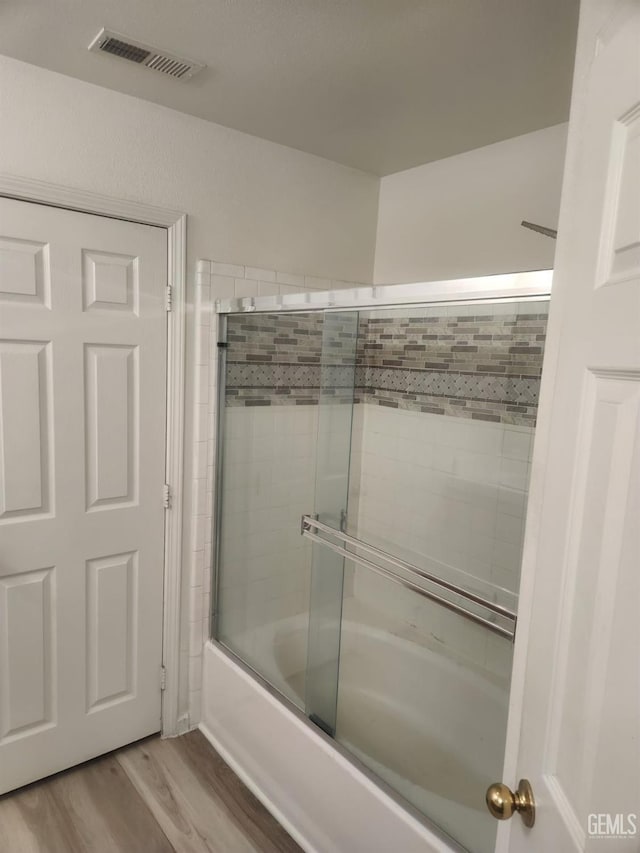 bathroom with enclosed tub / shower combo and wood-type flooring