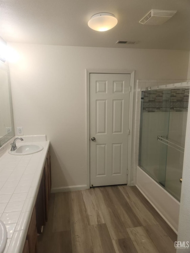 bathroom with enclosed tub / shower combo, vanity, and hardwood / wood-style floors