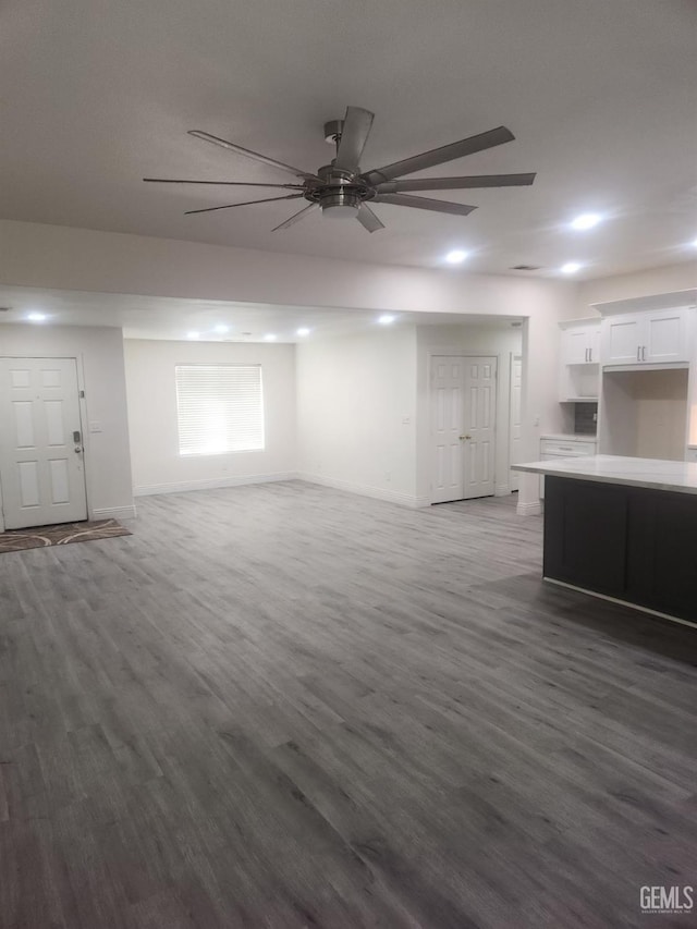 unfurnished living room featuring dark wood-type flooring and ceiling fan