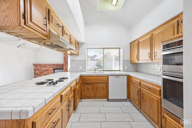 kitchen with backsplash, tile counters, and white appliances