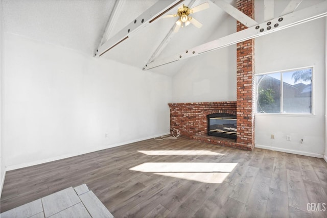 unfurnished living room with ceiling fan, a brick fireplace, beamed ceiling, high vaulted ceiling, and wood-type flooring