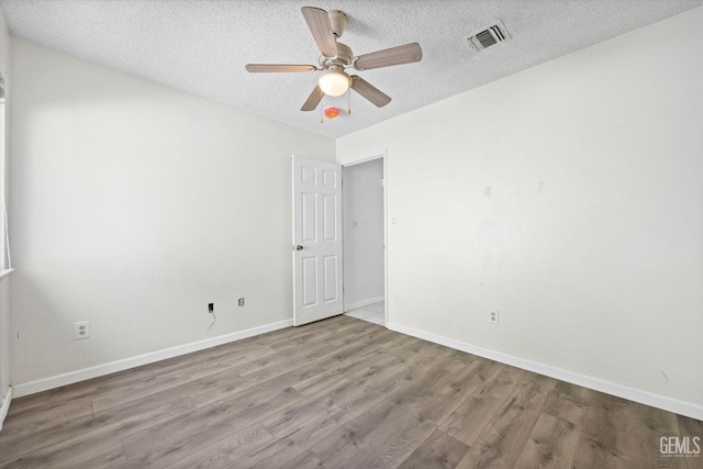 spare room with ceiling fan, light hardwood / wood-style flooring, and a textured ceiling