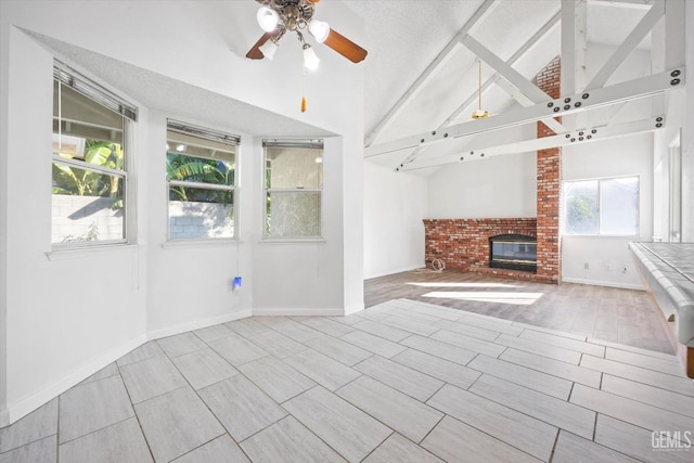 unfurnished living room with ceiling fan, a fireplace, high vaulted ceiling, and beamed ceiling