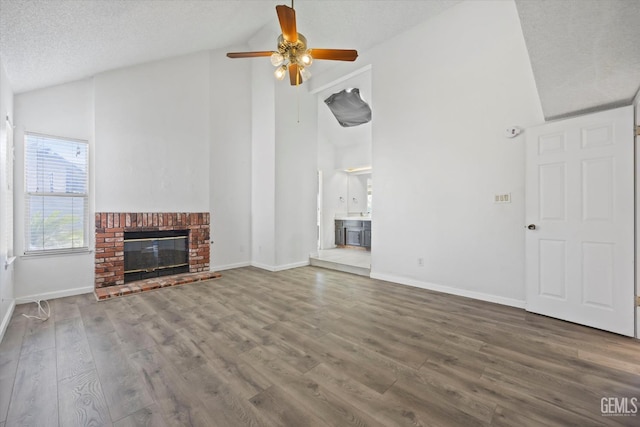 unfurnished living room with ceiling fan, wood-type flooring, high vaulted ceiling, and a brick fireplace