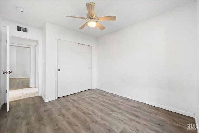 unfurnished bedroom featuring a closet, ceiling fan, and dark hardwood / wood-style flooring