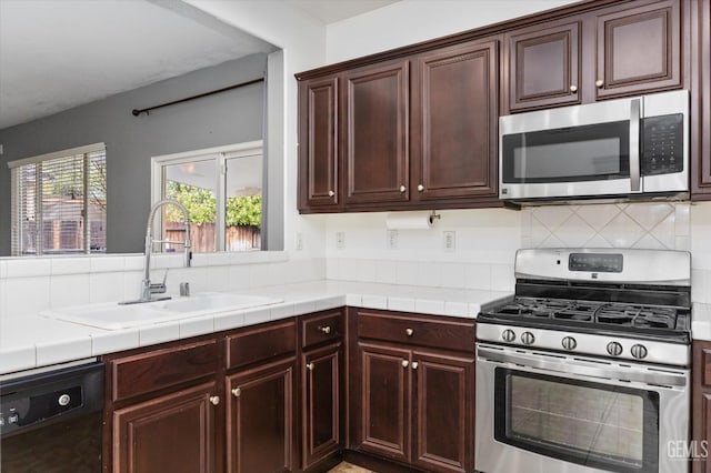 kitchen with a sink, backsplash, stainless steel appliances, dark brown cabinetry, and tile counters