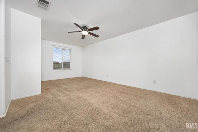 spare room with carpet flooring, a ceiling fan, and visible vents