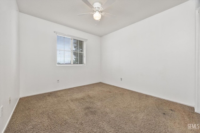 carpeted spare room featuring baseboards and ceiling fan