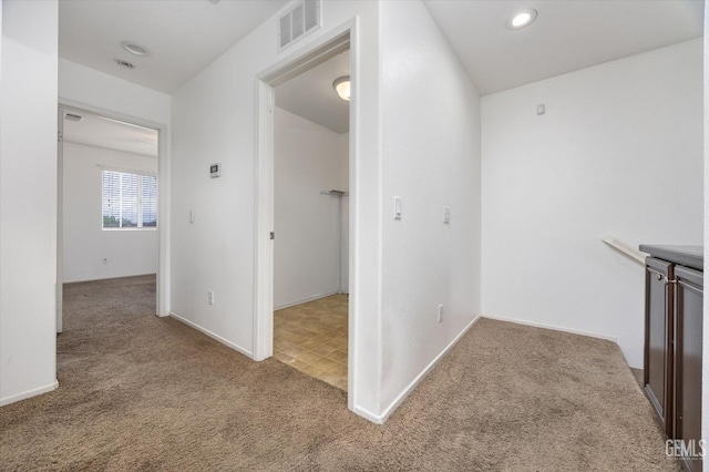 hallway with carpet, visible vents, and baseboards