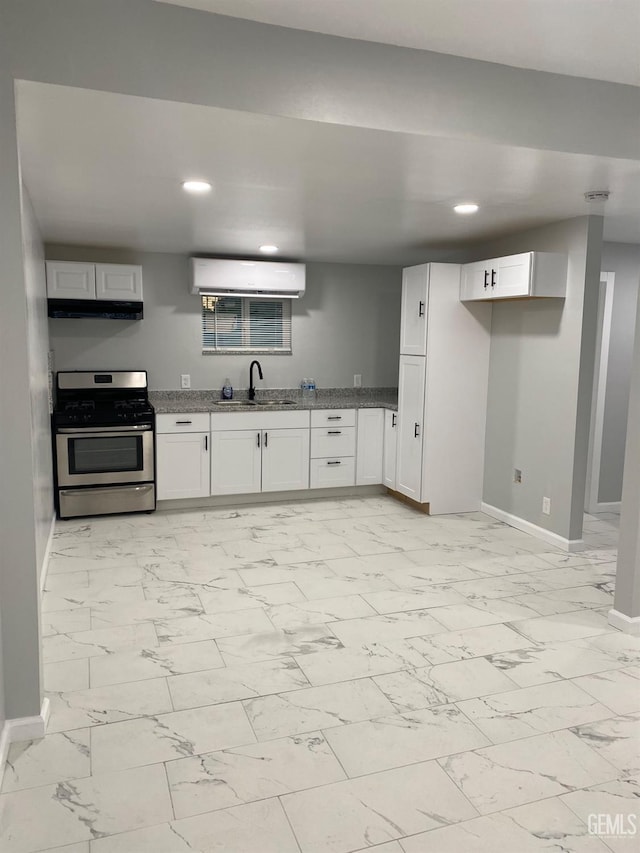 kitchen with sink, a wall mounted AC, white cabinets, gas stove, and light stone countertops