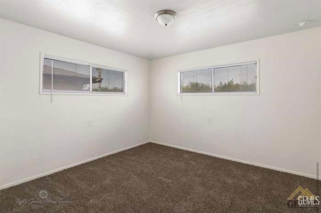 spare room featuring dark colored carpet