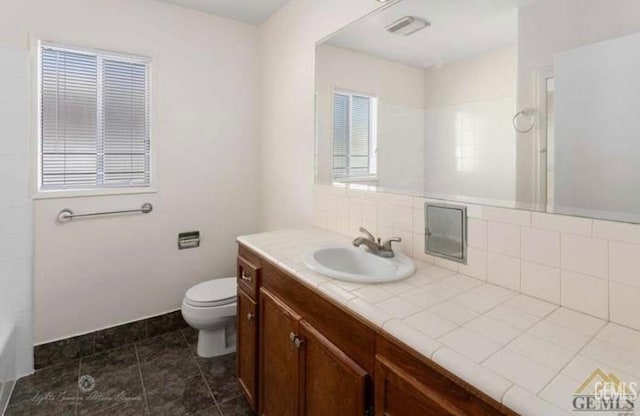 bathroom with vanity, backsplash, and toilet