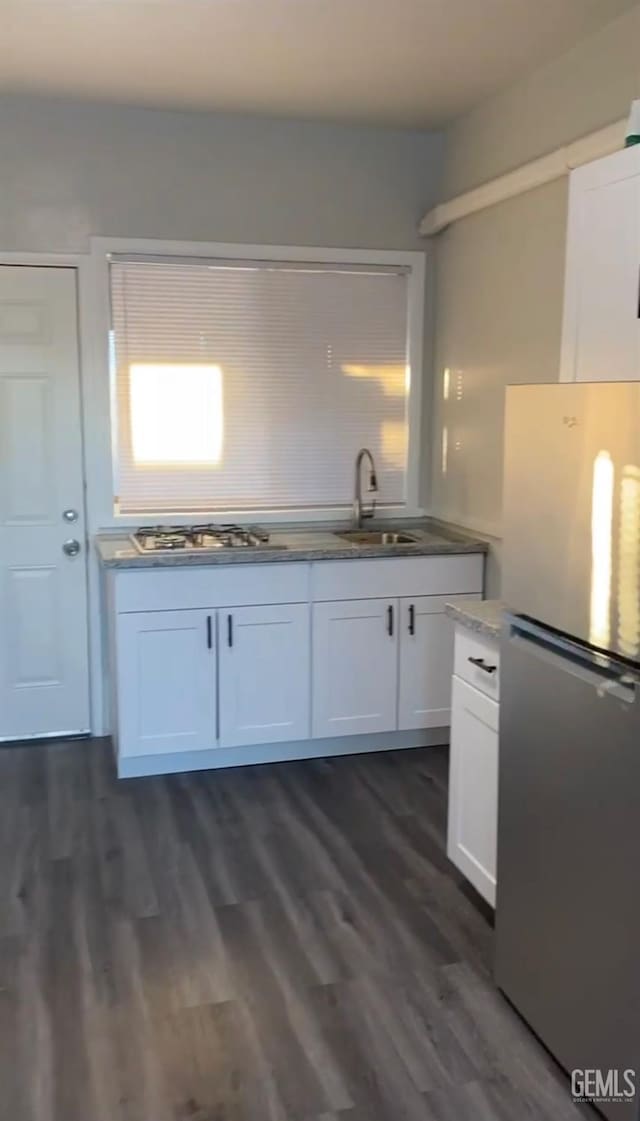 kitchen featuring stainless steel refrigerator, white cabinetry, dark hardwood / wood-style flooring, and sink