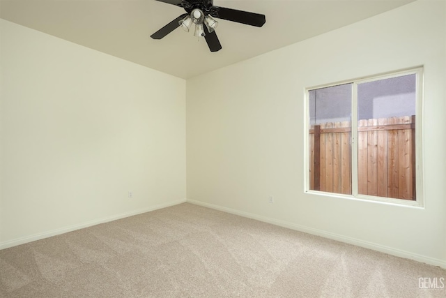 empty room with carpet flooring, a ceiling fan, and baseboards