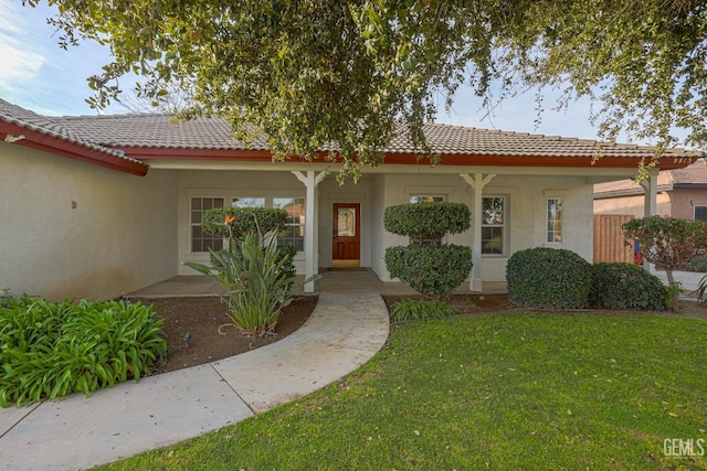 view of front of home featuring stucco siding, a tiled roof, and a front lawn