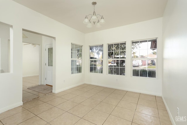 spare room with light tile patterned floors, a notable chandelier, and baseboards