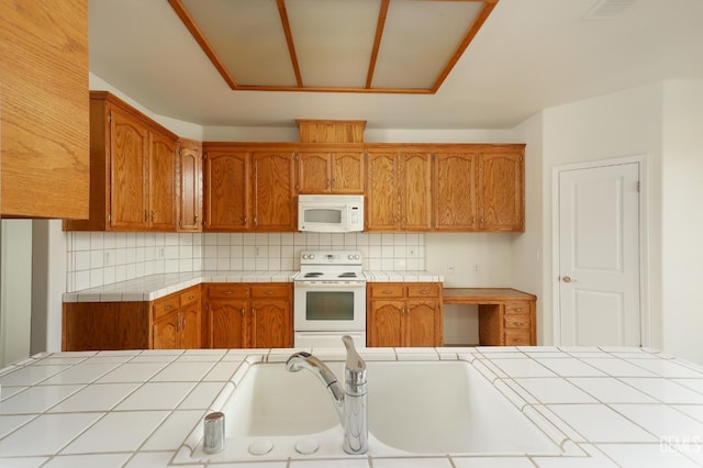 kitchen featuring brown cabinetry, decorative backsplash, tile countertops, and white appliances