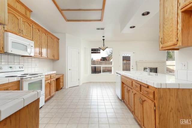 kitchen featuring white appliances, visible vents, a sink, tile counters, and backsplash