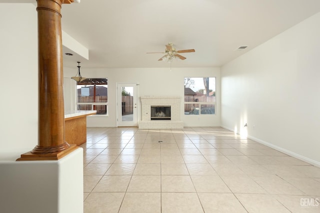 unfurnished living room with light tile patterned floors, plenty of natural light, ceiling fan, and decorative columns