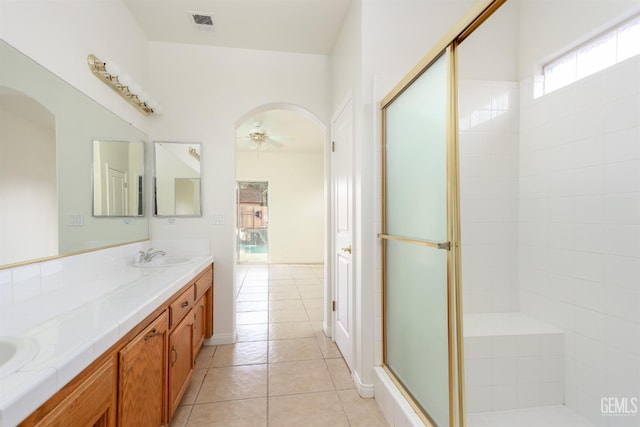 full bath with tile patterned floors, a stall shower, a ceiling fan, a sink, and double vanity