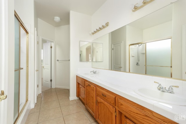 bathroom featuring tile patterned floors, double vanity, a shower with door, and a sink