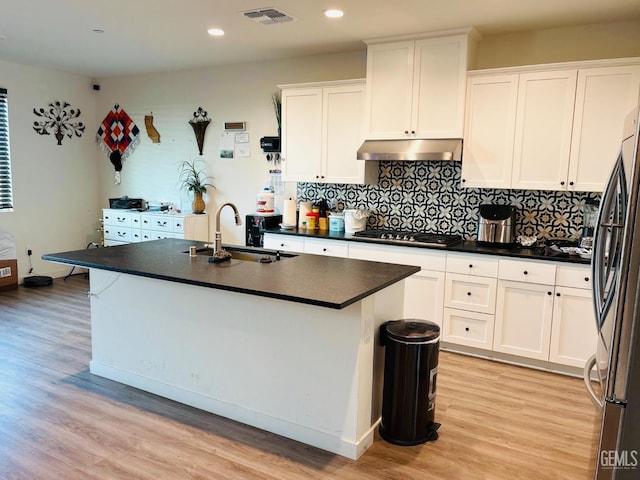 8410 Avon St, Bakersfield, CA 93314 - kitchen with appliances with stainless steel finishes, under cabinet range hood, white cabinetry, dark countertops, and light wood finished floors