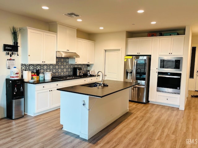 8410 Avon St, Bakersfield, CA 93314 - kitchen featuring appliances with stainless steel finishes, dark countertops, light wood finished floors, white cabinetry, and backsplash