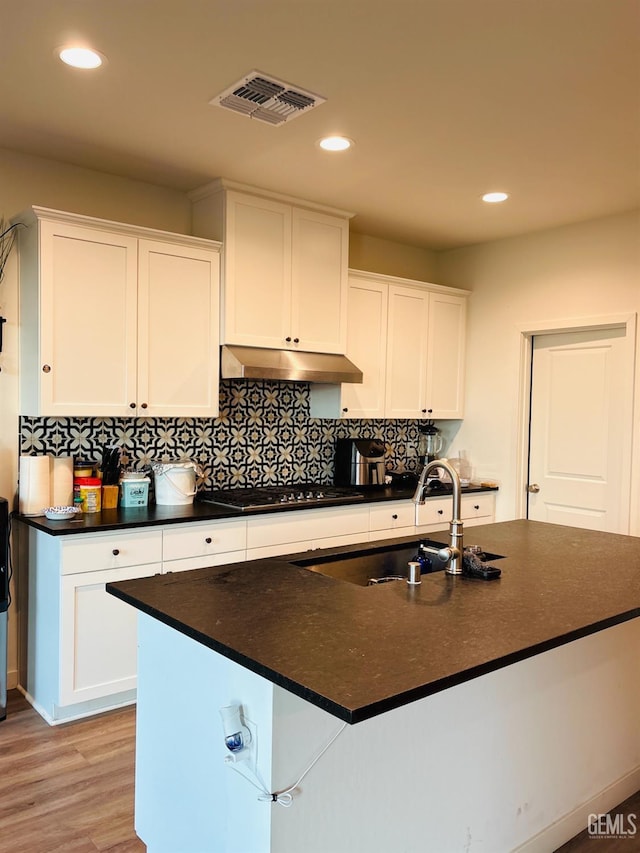 8410 Avon St, Bakersfield, CA 93314 - kitchen with cooktop, under cabinet range hood, dark countertops, white cabinets, and recessed lighting