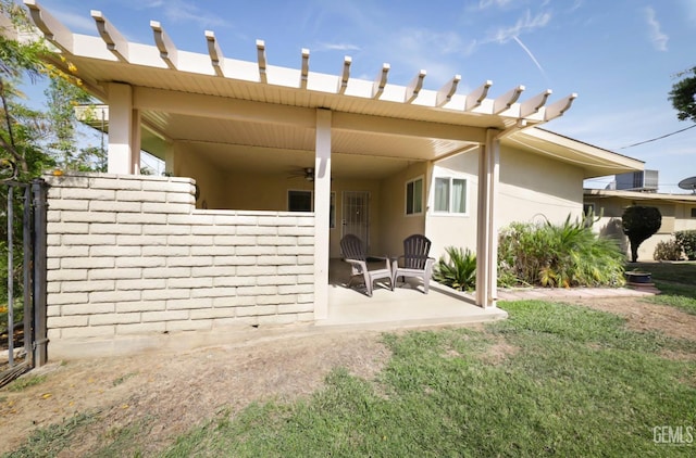 rear view of house featuring a yard, ceiling fan, a patio, and stucco siding