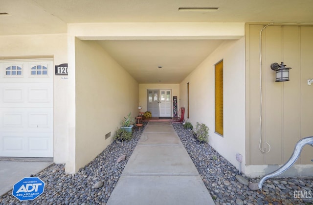 entrance to property with crawl space, an attached garage, and stucco siding