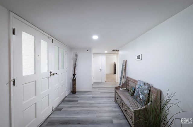 hallway with light wood finished floors, visible vents, and recessed lighting