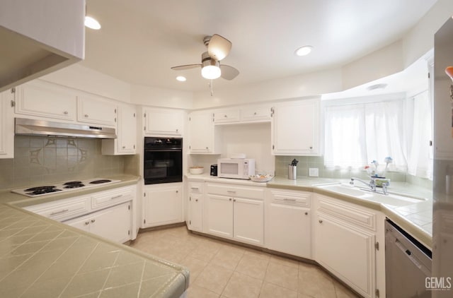 kitchen featuring white appliances, tile countertops, under cabinet range hood, white cabinetry, and a sink