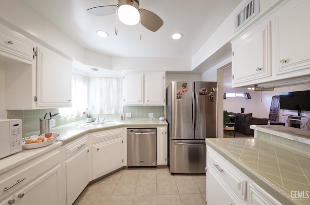 kitchen with stainless steel appliances, white cabinets, visible vents, and tile countertops