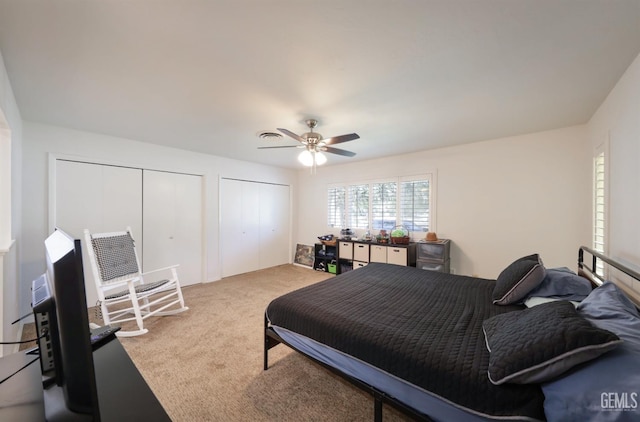 bedroom featuring a ceiling fan, light carpet, and two closets