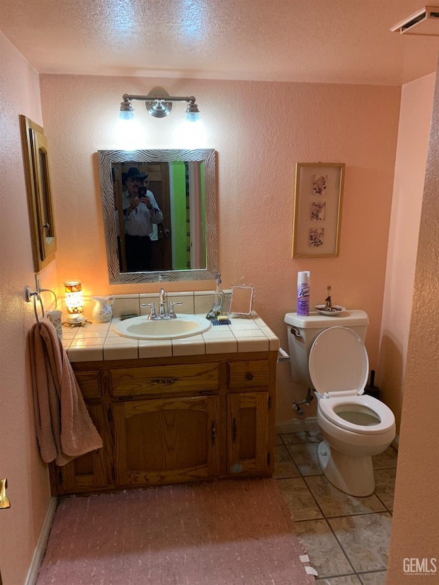 bathroom with tile patterned floors, vanity, a textured ceiling, and toilet