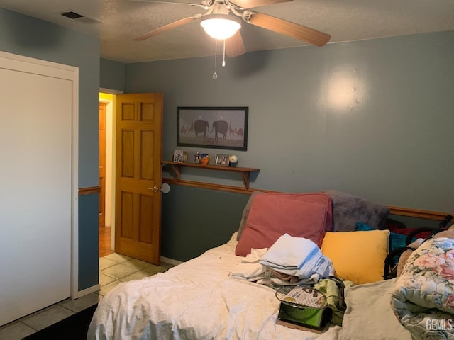 bedroom featuring light tile patterned floors, a textured ceiling, and ceiling fan