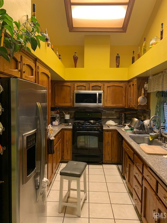 kitchen featuring black appliances, light tile patterned floors, and sink