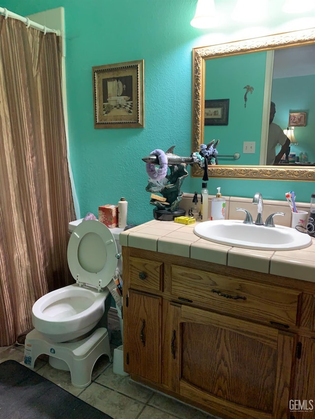 bathroom with toilet, vanity, and tile patterned floors