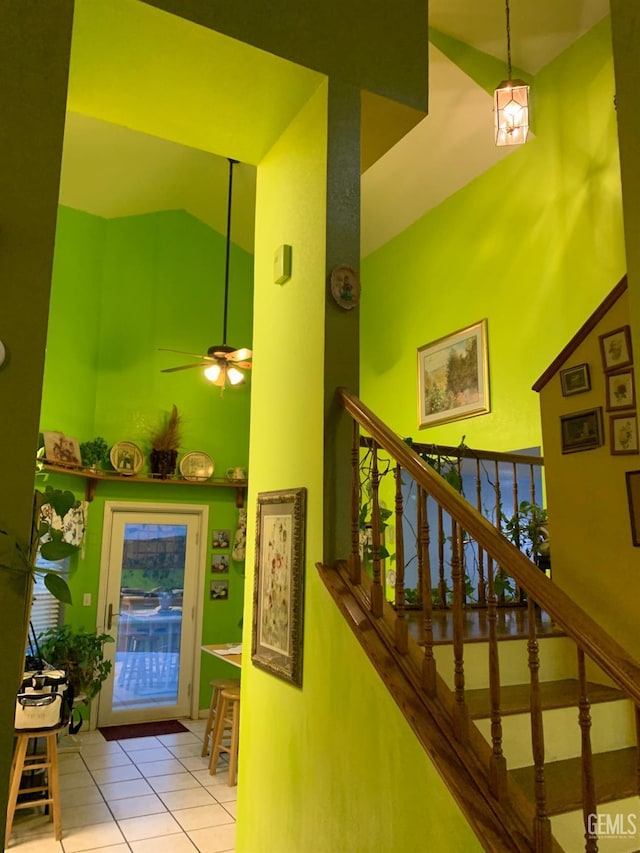 staircase with tile patterned floors, high vaulted ceiling, and ceiling fan