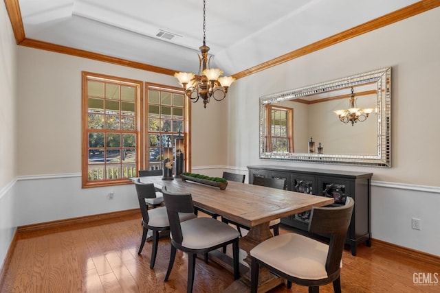 dining area featuring hardwood / wood-style floors, crown molding, and an inviting chandelier