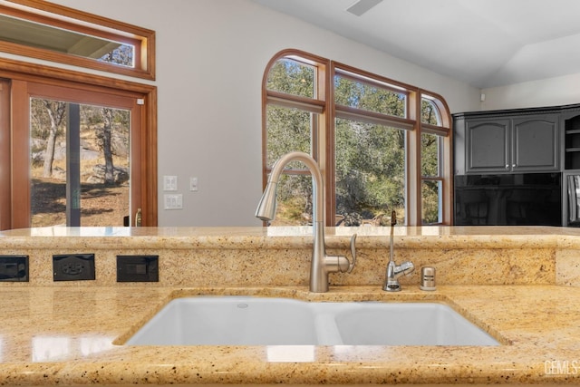 kitchen with light stone countertops, sink, and lofted ceiling