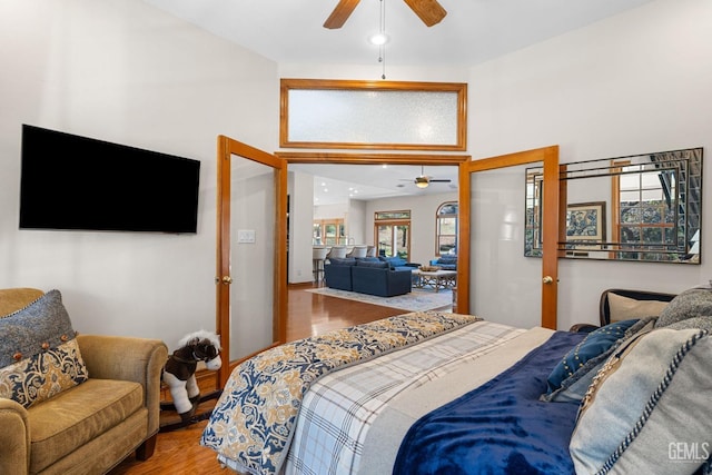 bedroom with ceiling fan, a towering ceiling, and wood-type flooring