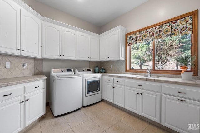 laundry room with washing machine and dryer, sink, light tile patterned floors, and cabinets