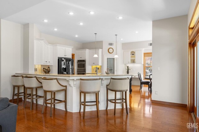 kitchen with black refrigerator with ice dispenser, white cabinets, kitchen peninsula, decorative light fixtures, and stainless steel double oven