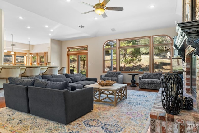 living room with ceiling fan with notable chandelier and wood-type flooring