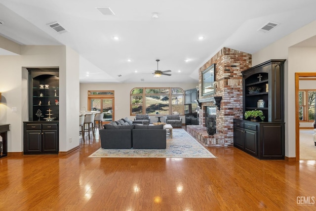 living room featuring a fireplace, light hardwood / wood-style flooring, plenty of natural light, and ceiling fan