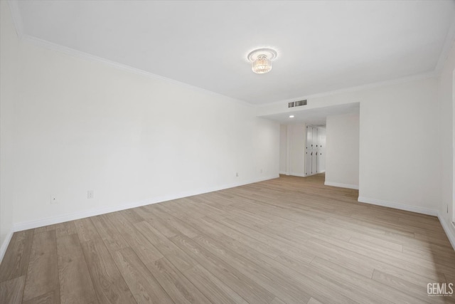 spare room with light wood-type flooring, visible vents, crown molding, and baseboards