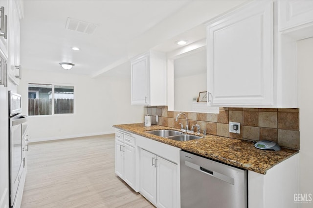 kitchen featuring a sink, white cabinetry, decorative backsplash, and dishwasher