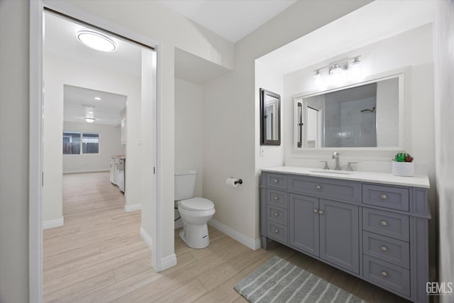 bathroom with toilet, baseboards, wood finished floors, and vanity