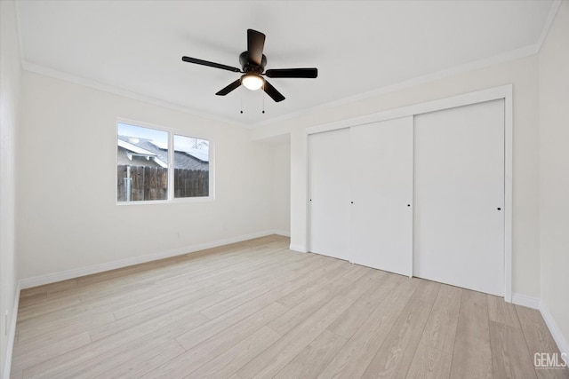 unfurnished bedroom with ornamental molding, a closet, light wood-style flooring, and baseboards